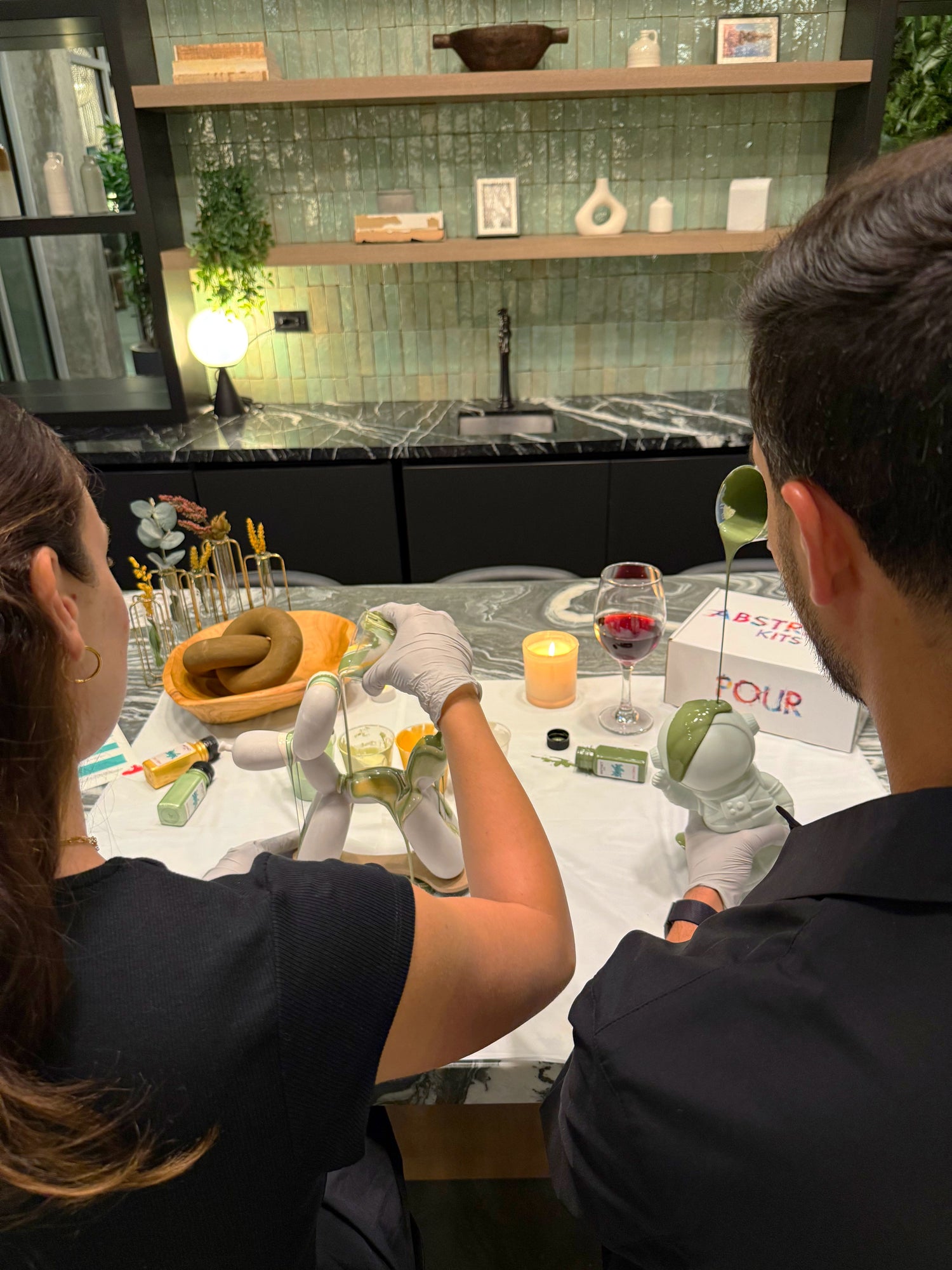 Couple enjoying a creative date night activity using Abstract Kits' DIY fluid art kit, smiling while pouring colorful paint together.